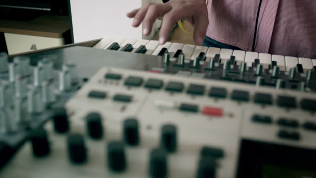 Making music. Man playing on keyboard connected to audio mixer