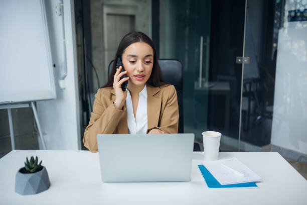 istock Caucasian woman with black hair discussing work issues during business conversation on smartphone. Pleasant helpline worker offering solution to problem at workplace. 1983436546