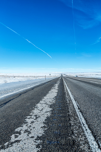 Long, long, long distance diminishing perspective highway view from road surface level on a cold January mid-afternoon looking eastward along Interstate Route 80 expressway in Wyoming, USA.