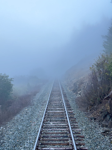 Medium POV shot from a train as train tracks disappear into a thick fog