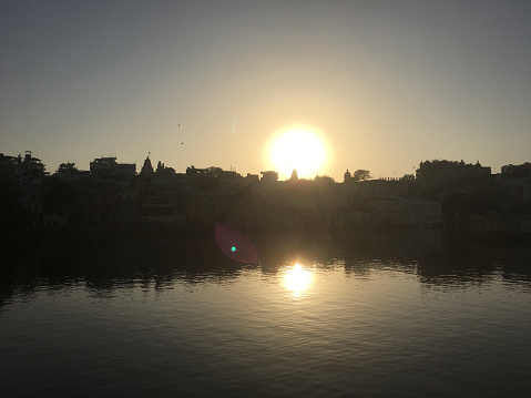 Sunrise over calm lake and city on Lake Pichola