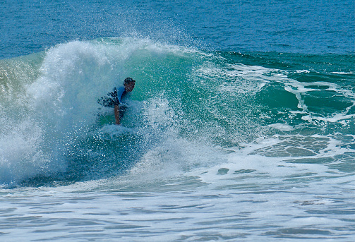 Surfer on his backside in the tube of a frothy wave in Newport Beach