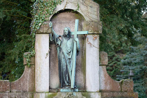 statue of jesus on a historic tomb with large cross and outstretched hand towards heaven