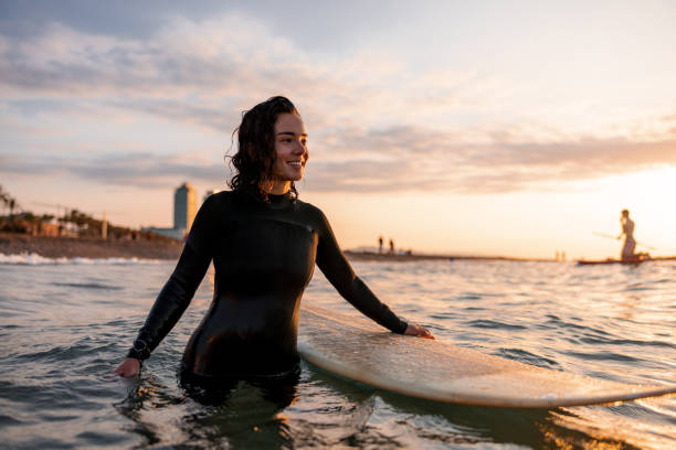 istock Happy Female Surfer Preparing To Catch Waves During Sunrise 1983739894