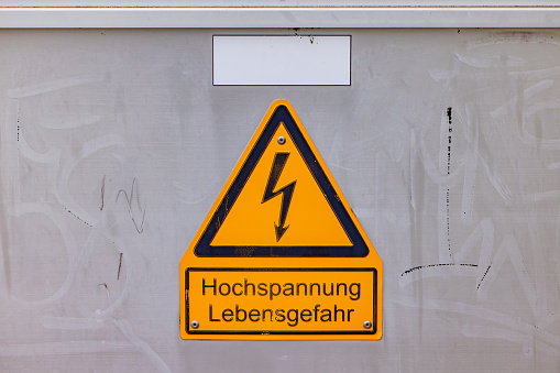 Yellow sign warning high voltage danger to life on electrical box with German text