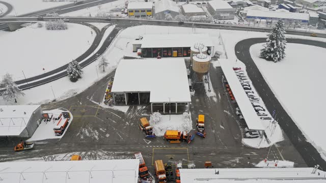 Aerial view of snowed it highway maintenance center with snow ploughing trucks