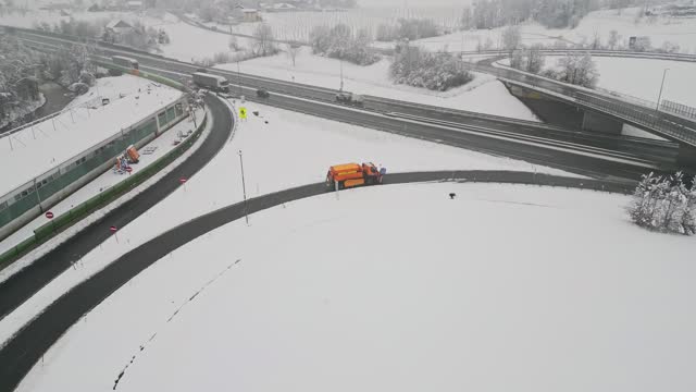 Aerial view of orange snow ploughing truck going on the highway