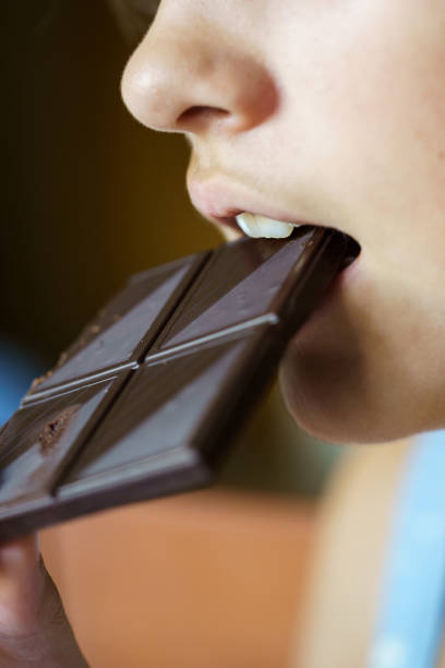 istock Anonymous girl biting yummy chocolate bar at home 1983824897