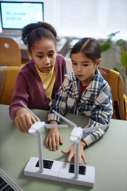 istock Two Schoolgirls Playing with Wind Turbine Model During Class 1983837483