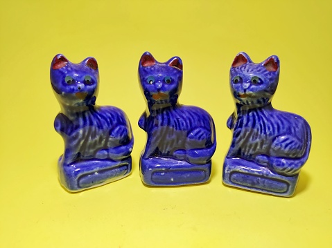 Blue porcelain cat figurine on yellow background. close up shots