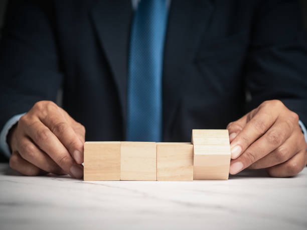 istock Businessman hold four blank wooden cubes while sitting at the table. 1984064641