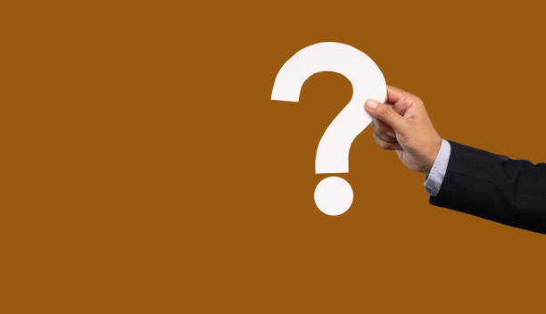 istock Hand holding a white question mark symbol against a brown background. 1984064645