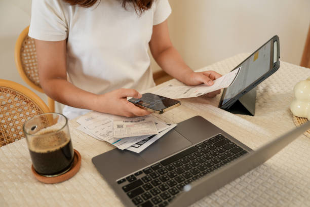 Woman's hand calculating monthly expenses on smartphone