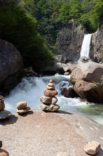 a small rock sculpture of  stacked rocks on a boulder with a lush forest and waterfall in the background