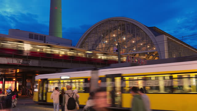 4K Footage Time lapse of Crowd of People tourist walking and crossing road and tram station at Alexanderplatz a large public square and transport hub in the central Mitte district of Berlin, Germany