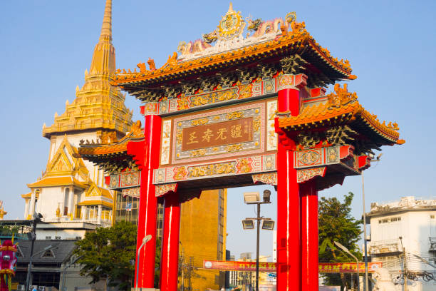 Red colored landmark Chinese gate and Wat Traimit  in Bangkok Red colored landmark Chinese gate and Wat Traimit  in Bangkok in late afternoon sunshine. Gate is located opposite to backside of Wat Traimit and near to Yaowarat Rd in Chinatown. Full name of temple  is Wat Traimit Withayaram Worawihan (Golden Buddha). Main entrance is at Charoen Krung Road, true thailand classic stock pictures, royalty-free photos & images