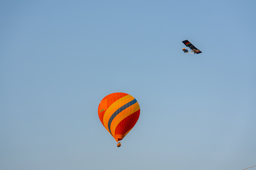 Small airplane and hot air balloon flying on the background of clear blue sky