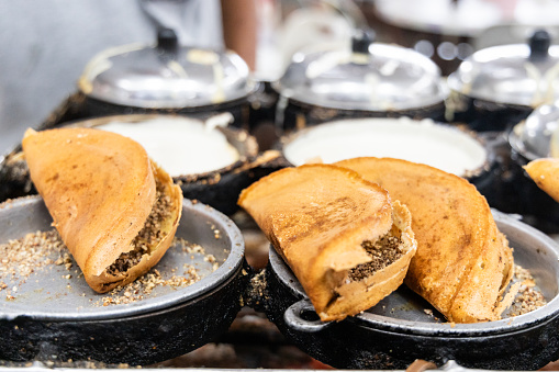 Vendor preparing traditional delicious apam balik or peanut pancake in food eatery. Popular snack in Malaysia, Singapore and Indonesia.