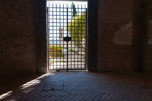 Urbino Italy May 17 2011; steel see-through gate with view from inside to sunny gardens and outdoors