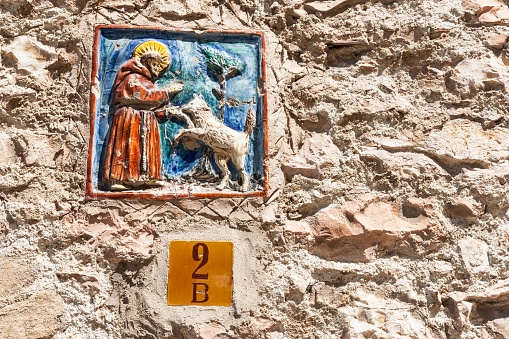 Assissi Italy May 18 2011;  Plaque on exterior boundary wall on street with ceramic image of St Frances of Assissi the parton saint of animals