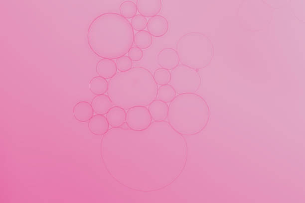 A created abstract diagram produced by adding oil droplets to water surface to create an interesting collection of different sized bubbles highlighted by adding pale pink coloured lighting.