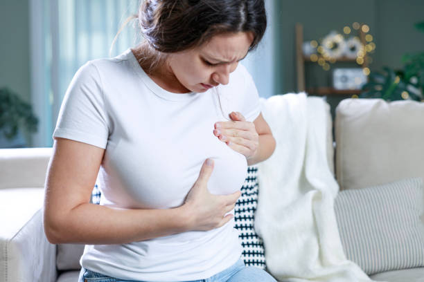 istock Young clothed woman doing preliminary breast self-check at home 1984443200