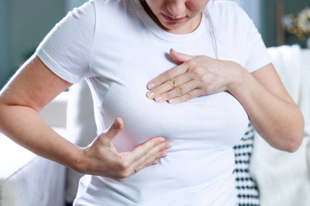 istock Young clothed woman doing preliminary breast self-check at home 1984443201