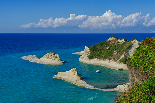 Small blue and white boat in Cape Drastis bay, Corfu, view from above, horizontal