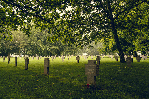 German war graves resting peacefully under green trees at the Recogne war cemetery in Bastogne, Belgium.  Battle of the Bulge