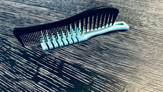 Two combs interlocked on a black wooden table