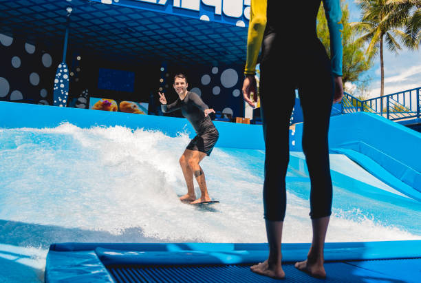 istock Young man surfing with trainer on a wave simulator at a water amusement park 1984532200
