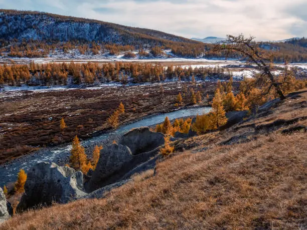 Photo of Motley autumn landscape with sunlit hills, blue river and mountain range