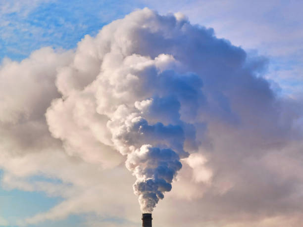 istock A thick smoke is rising up from the pipe on a blue sky background 1984619463