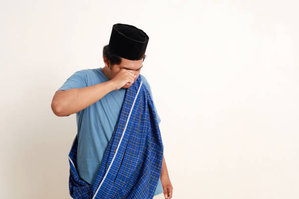 Sad asian muslim boy standing while crying. Isolated on white with copyspace