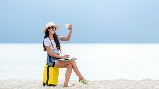 Happy traveler and tourism young women travel summer on the beach. Asian smiling people holding smartphone take photo  for relax outdoor destination leisure trip travel in holiday