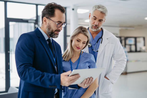 istock Pharmaceutical sales representative talking with doctors in medical building, presenting new medication on tablet. Hospital director, manager in modern clinic with doctor and nurse. 1984698643