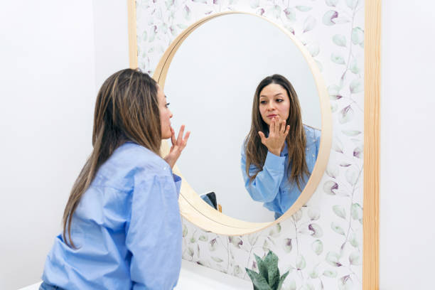 istock Satisfied Female Client Checking Skin Texture in Mirror Post Aesthetic Procedure 1984739661
