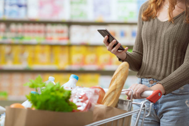 istock Woman doing grocery shopping and using her smartphone 1984791648