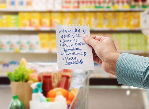 Woman at the supermarket buying groceries and holding a shopping list, point of view shot