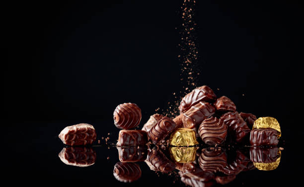istock Various chocolate candies on a black background sprinkled with chocolate chips. 1984915792