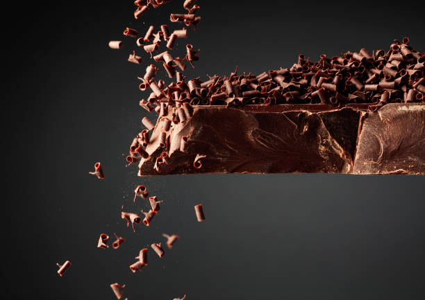 Large piece of dark chocolate and falling chocolate crumbs. Large piece of dark chocolate and falling chocolate crumbs on a black background. bittersweet berry stock pictures, royalty-free photos & images