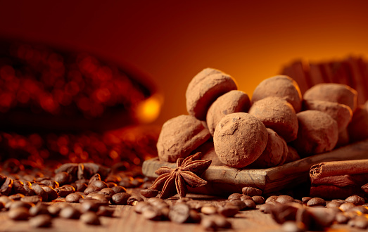 Delicious chocolate truffles with cinnamon, anise, and coffee beans on a old wooden table.