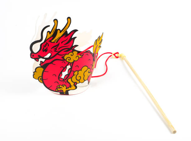 An Asian senior woman is carefully painting Dragon Sculpture Joss stick in factory using vibrant colours
