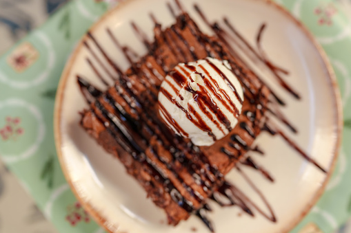 A slice of brownie with vanilla icecream on top.