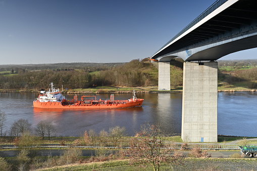 Red freighter passes a bridge on the Kiel Canal