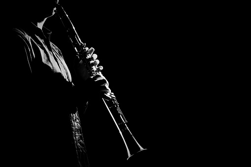 Clarinet player hands. Clarinetist playing woodwind music instrument closeup on black background