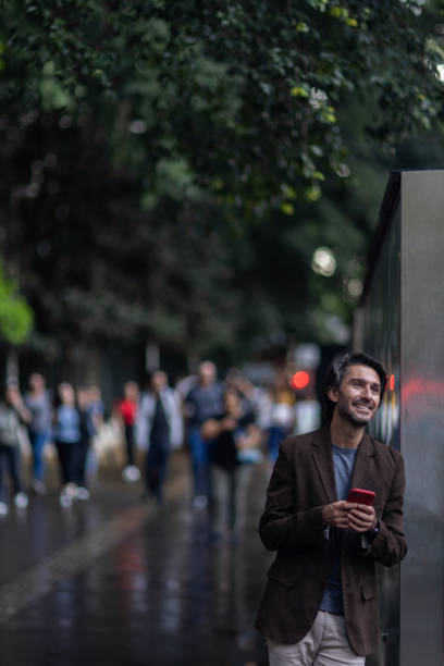 View of young man with smartphone at daytime with city view landscape in the background. High quality photo.
