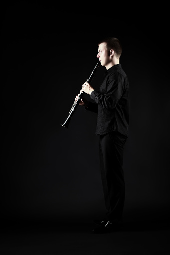Clarinet player classical musician. Man playing clarinette woodwind instrument full length