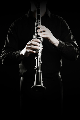 Clarinet player. Clarinetist hands playing woodwind music instrument close up isolated on black