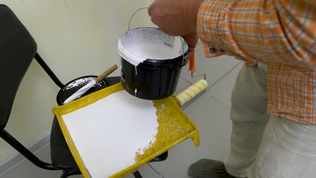 A man prepares white paint to paint a wall.